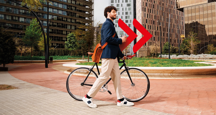 uomo con cartella a tracolla che trasporta a mano una bicicletta