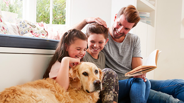 Padre e figli che giocano sorridenti con il cane 